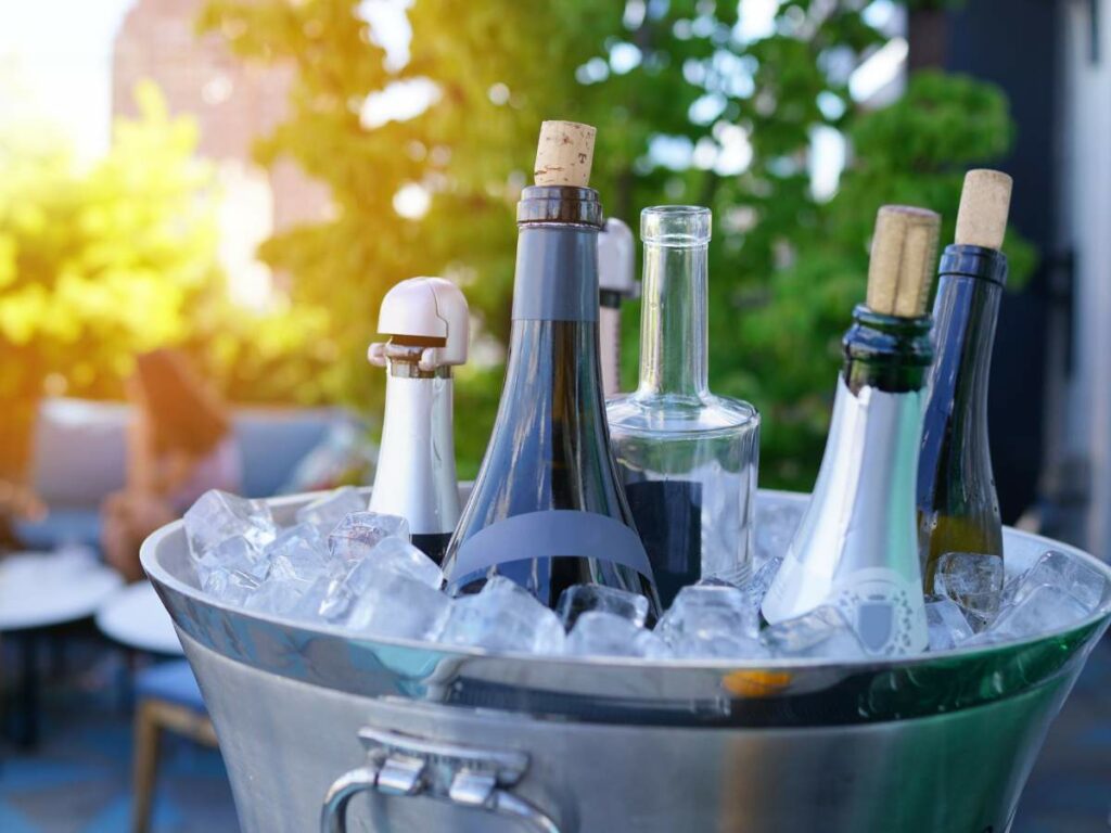 A metal bucket filled with ice holds several bottles, some with corks and some with caps.