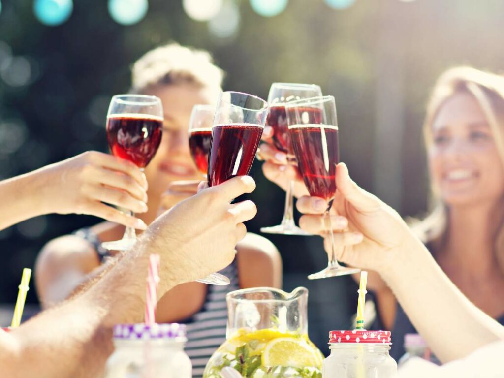 People clinking glasses of red wine in a celebratory toast outdoors.