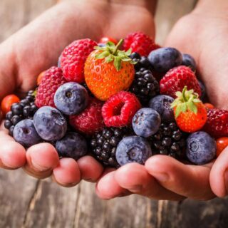 Hands holding an assortment of fresh berries.