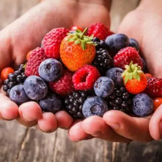 Hands holding an assortment of fresh berries.