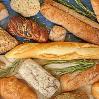 A variety of bread types are displayed on a blue surface.