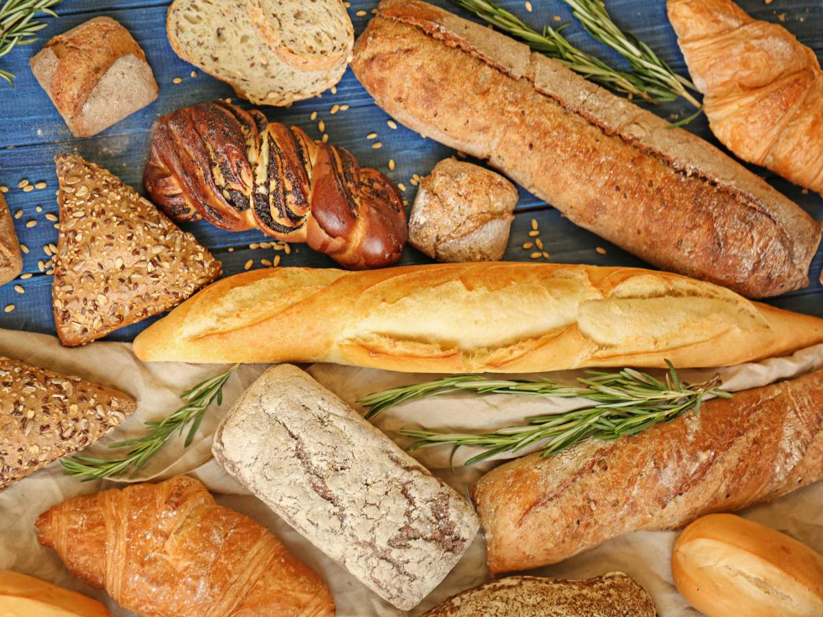 A variety of bread types are displayed on a blue surface.