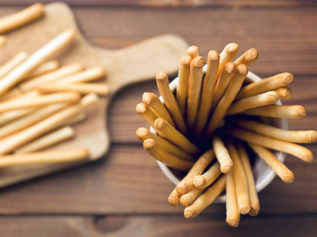 Top view of a cup filled with breadsticks on a wooden surface.