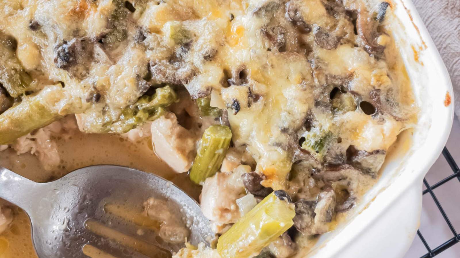 A close-up of chicken asparagus casserole with melted cheese, mushrooms, asparagus, and pieces of chicken.