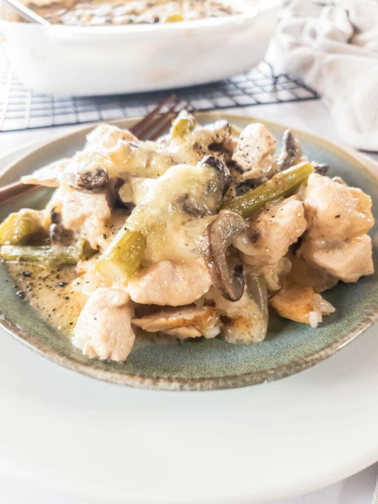 A plate of chicken asparagus casserole with mushrooms and vegetables, served on a greenish-gray ceramic plate.