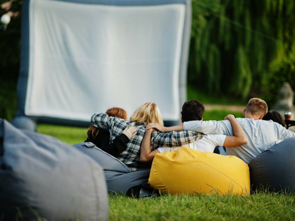 Four people sitting close together on colorful bean bags with their arms around each other.