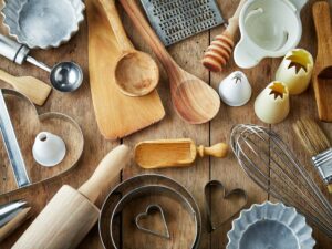 A variety of kitchen utensils are scattered on a wooden surface.