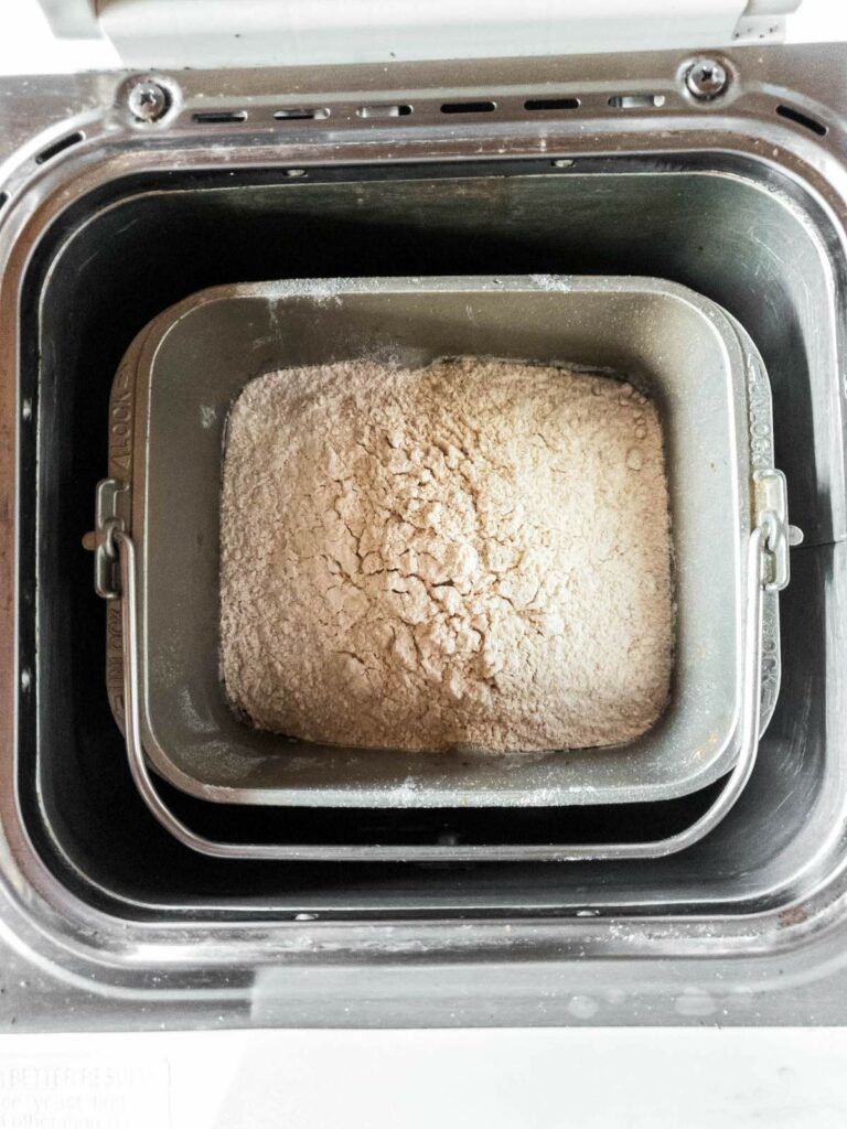 An open bread machine filled with flour mixture.