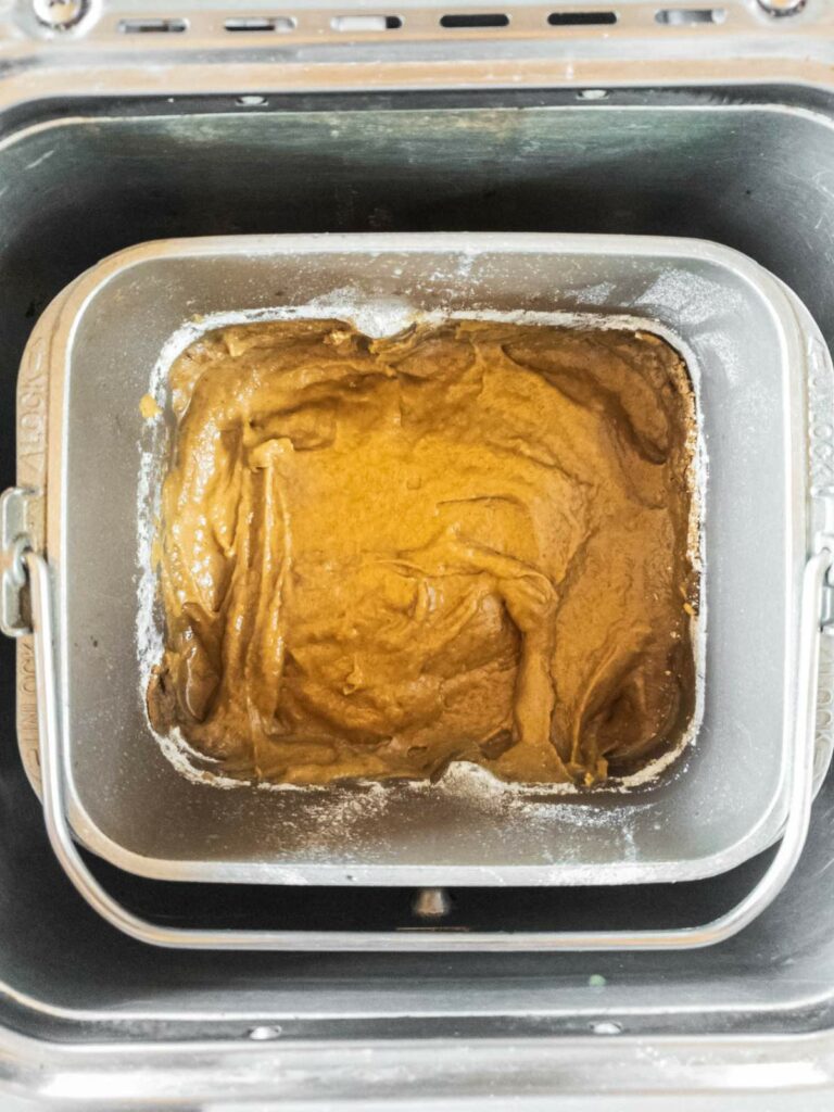 Close-up of raw batter in a bread machine pan, ready for baking.