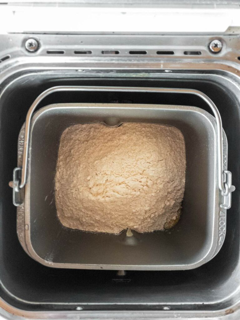 A bread machine with a mixing container holding ingredients.