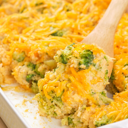 A wooden spoon scooping a serving of broccoli rice casserole.