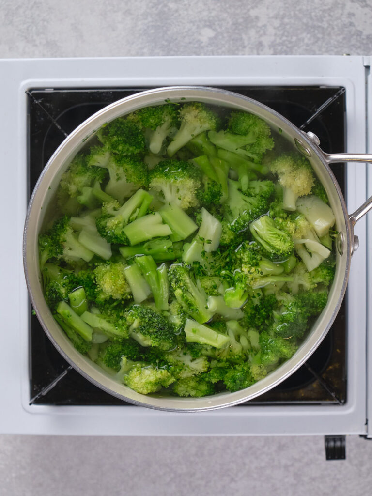 A pot of broccoli pieces being boiled on a stove.