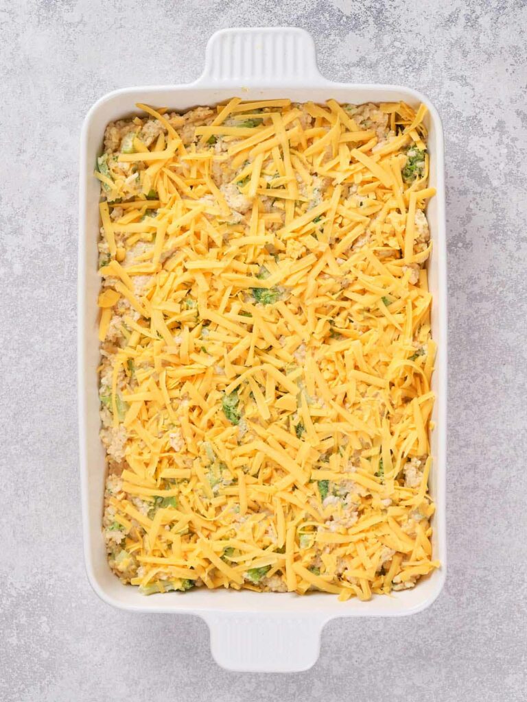 A casserole dish filled with broccoli rice casserole on a gray textured surface.