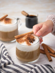 A person holding a cup of dirty chai tea latte.