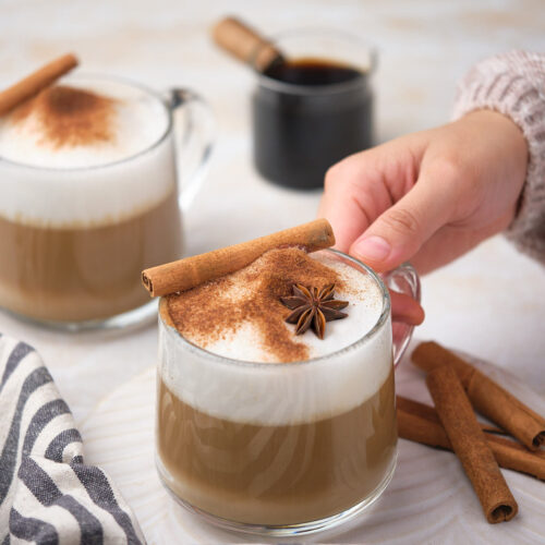 A person holding a cup of dirty chai tea latte.