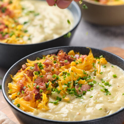 A close-up of a bowl of potato soup topped with garnish.