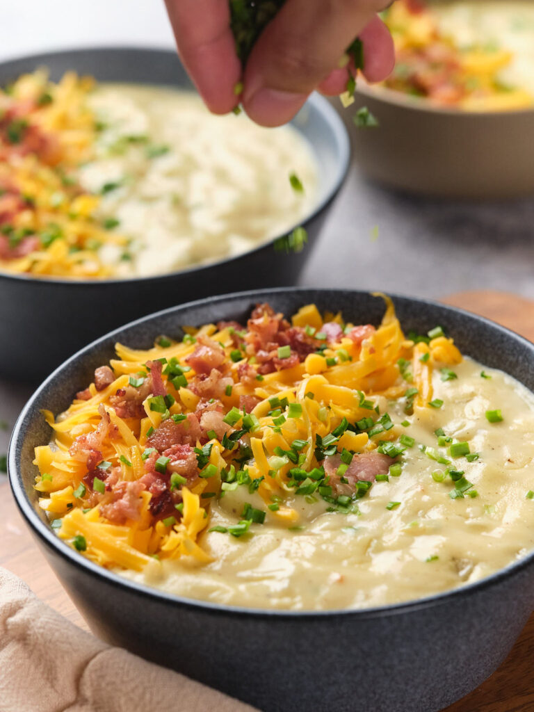 A close-up of a bowl of potato soup topped with garnish.