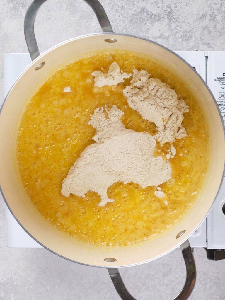 A pot on a stove containing a mixture of melted butter and dry ingredients.