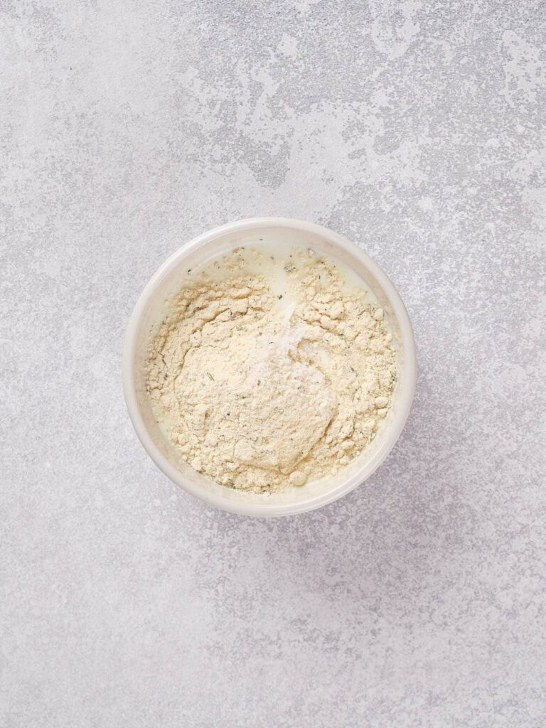 A bowl of dry ingredient on a light grey textured surface.