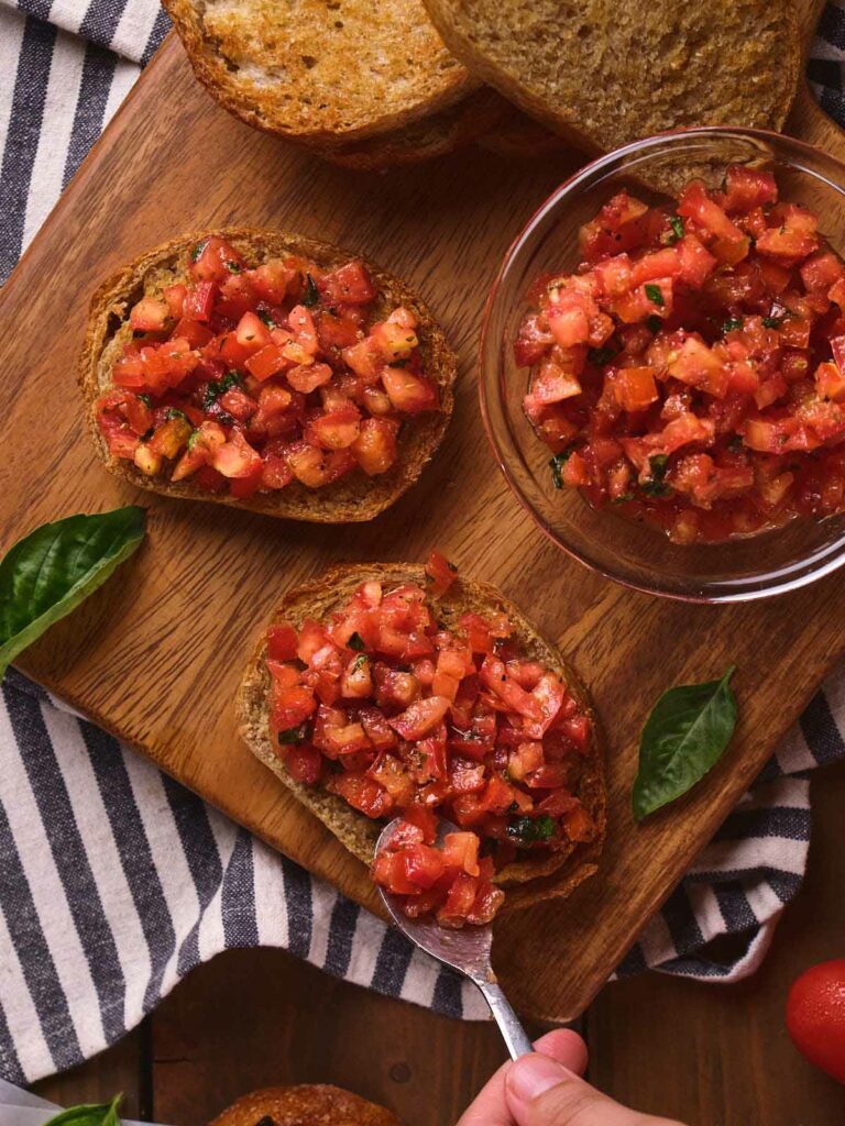 Two slices bruschetta al pomodoro and additional toast slices.