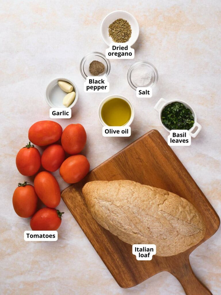 Ingredients for bruschetta al pomodoro are laid out on a light colored surface.