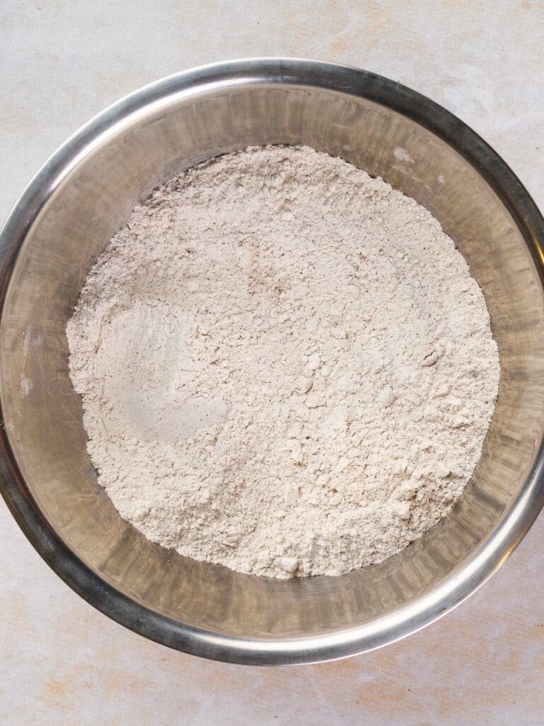 A stainless steel bowl filled with a mixture of dry ingredients.