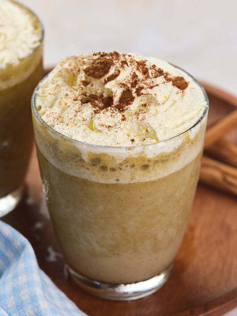 A glass of iced pumpkin spice frappuccino topped topped with whipped cream.