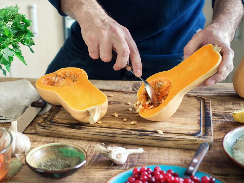 A person taking the seeds out of a squash.