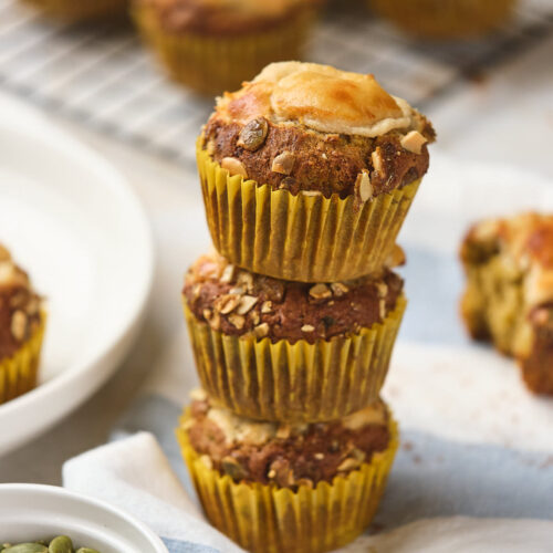 Three pumpkin and cream cheese muffins stacked on a napkin.