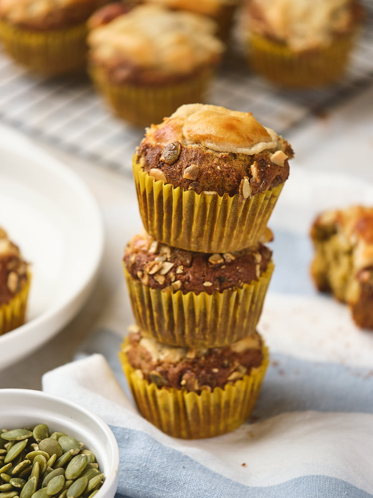 Three pumpkin and cream cheese muffins stacked on a napkin.