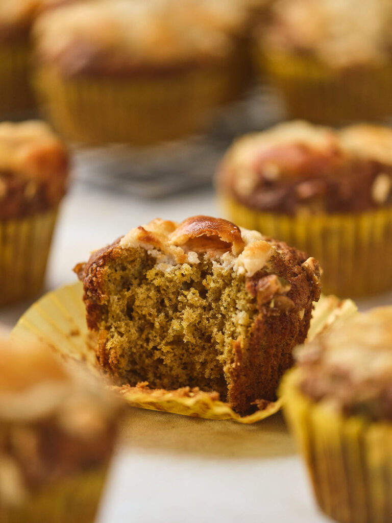 A close-up of a pumpkin and cream cheese muffin with a partially eaten top.