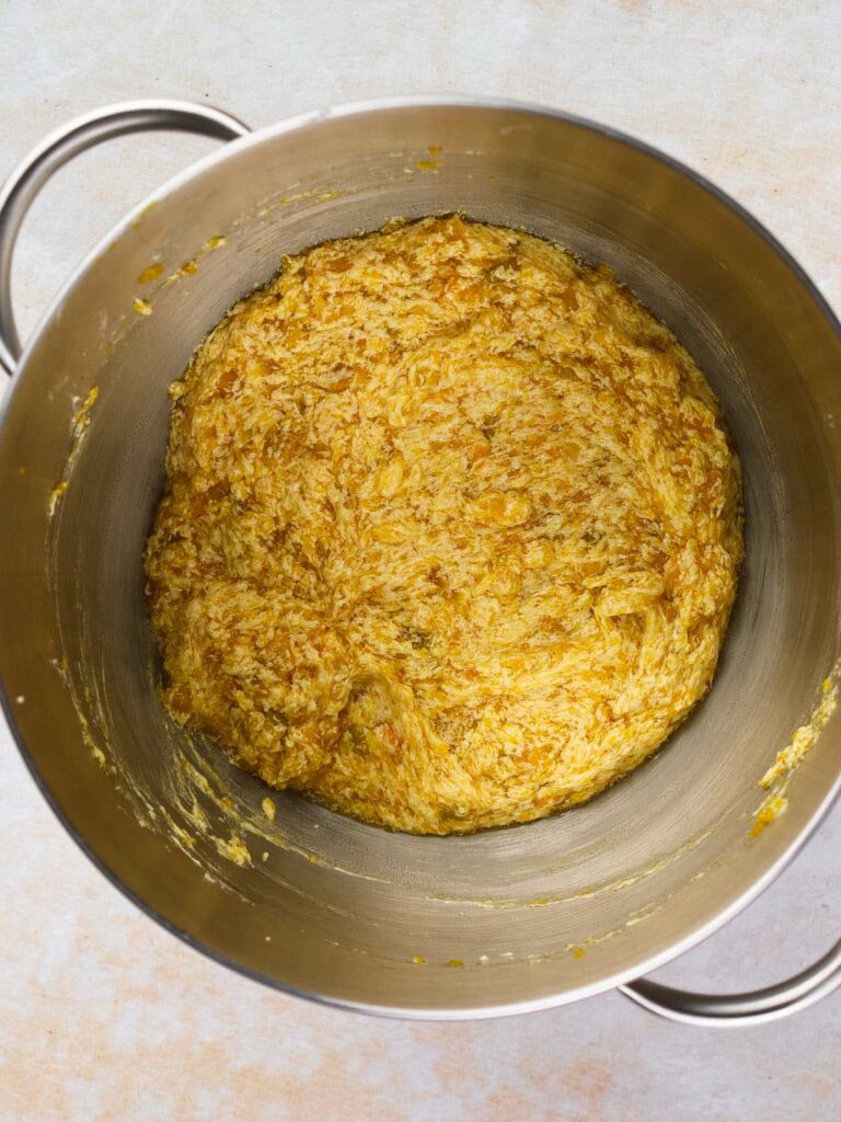 A large stainless steel mixing bowl filled with a thick, textured yellow-orange mixture.