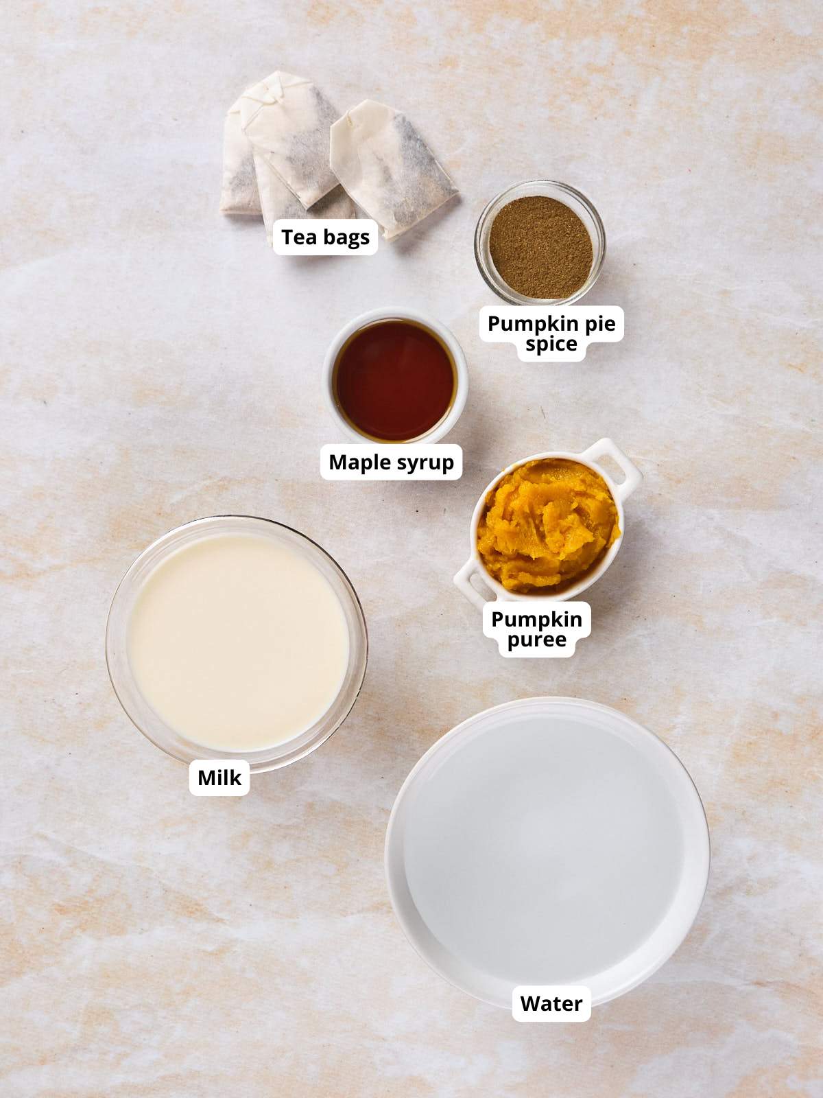 Ingredients for pumpkin spice chai tea latte displayed on a surface.