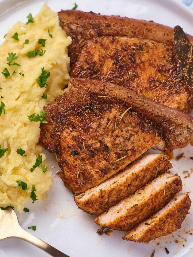 A serving of seasoned pork chops on a white plate.