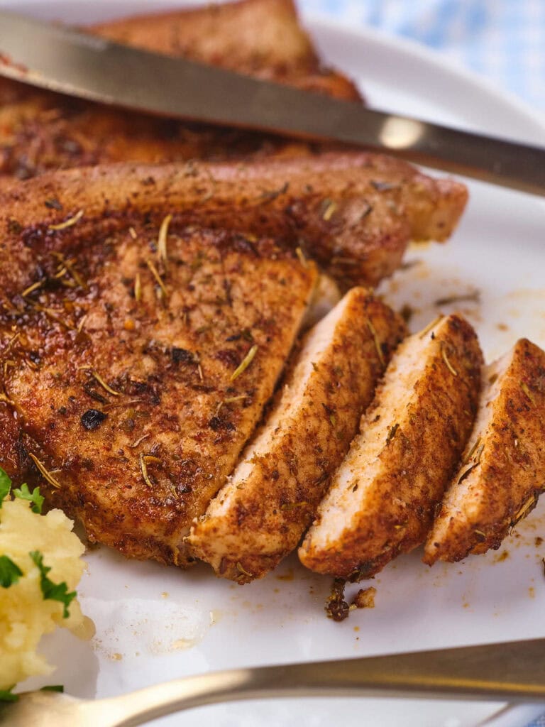 Pork chop with a portion of it sliced into pieces.