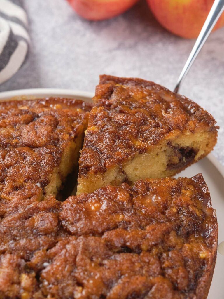 Close-up of a sliced apple cinnamon cake, showing a moist texture and a caramelized top.