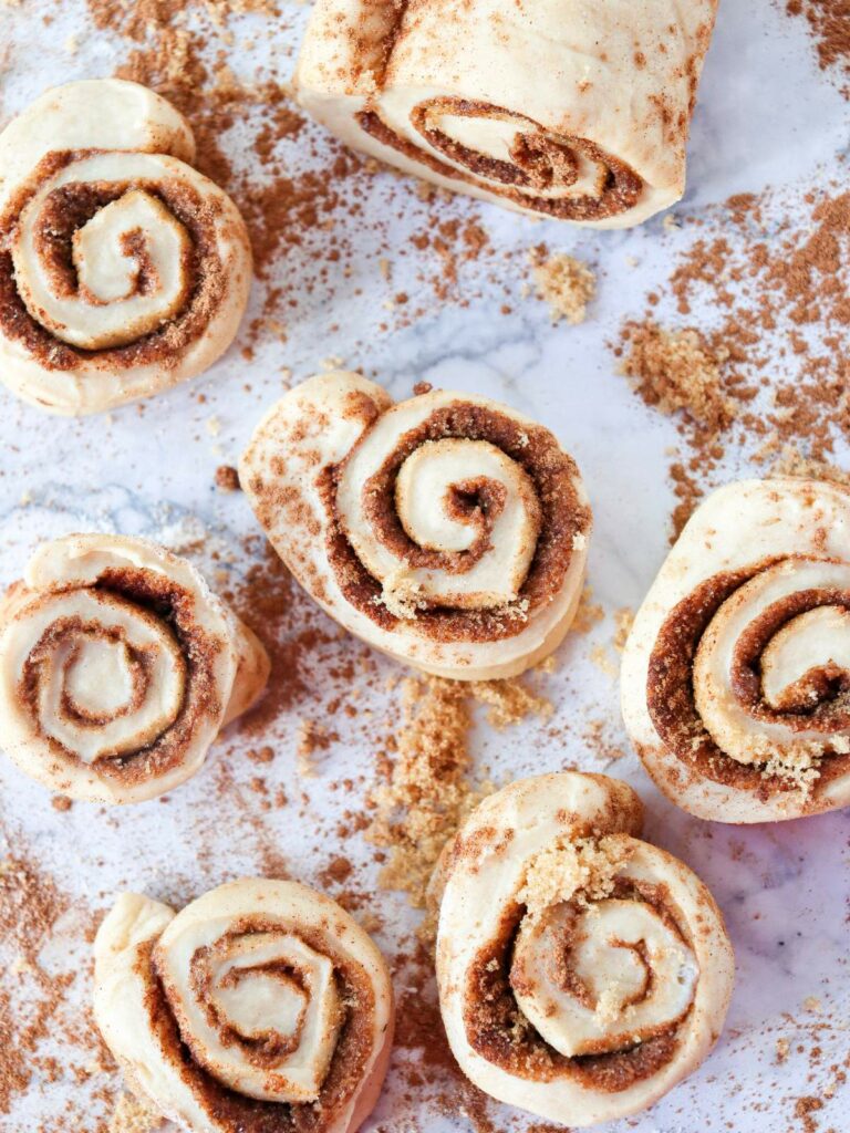 Unbaked cinnamon rolls with brown sugar and cinnamon filling on a floured surface.