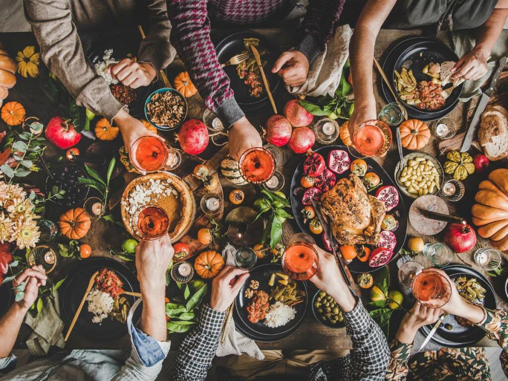 People seated around a table filled with autumn-themed food and drinks, holding glasses up for a toast.