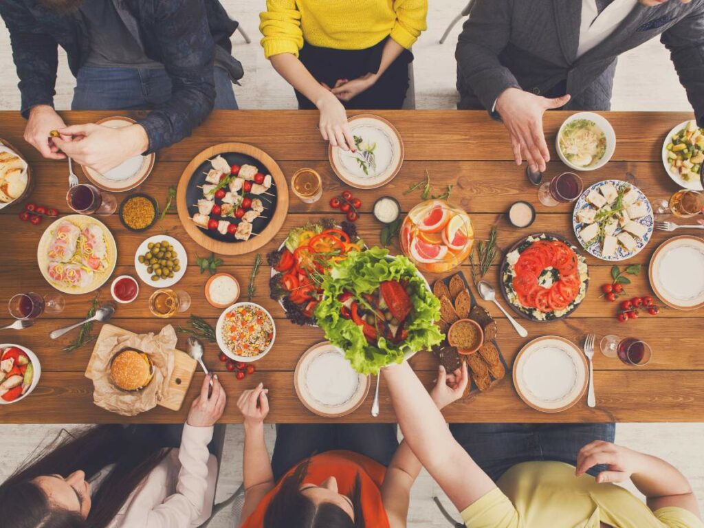 Top view of a group of people sitting around a wooden table filled with various dishes.