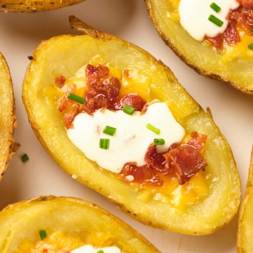 Potato skins topped with melted cheese, bacon, sour cream, and chopped chives.