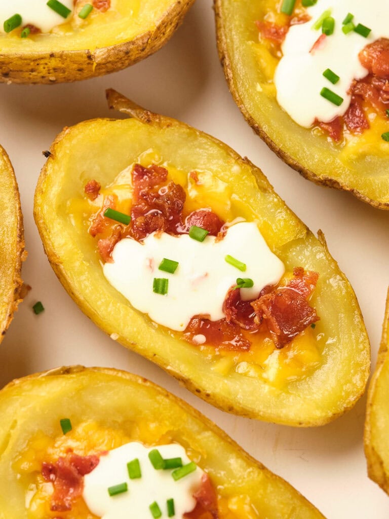 Potato skins topped with melted cheese, bacon, sour cream, and chopped chives.