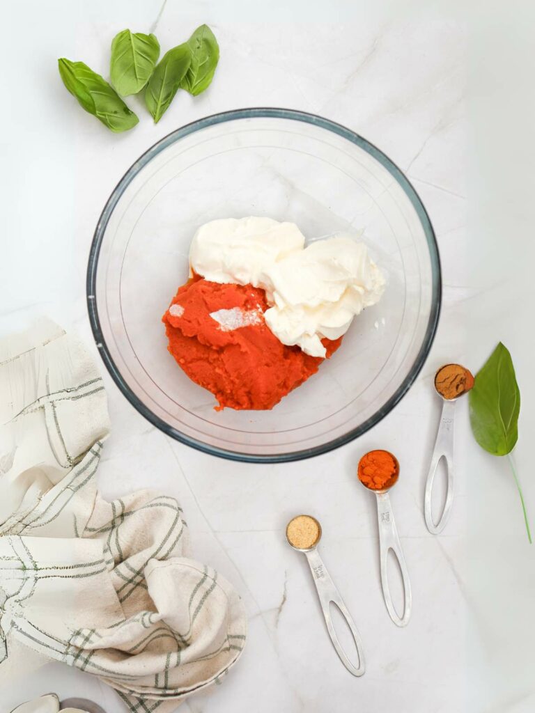 A glass bowl contains white and red ingredients on a marble surface.