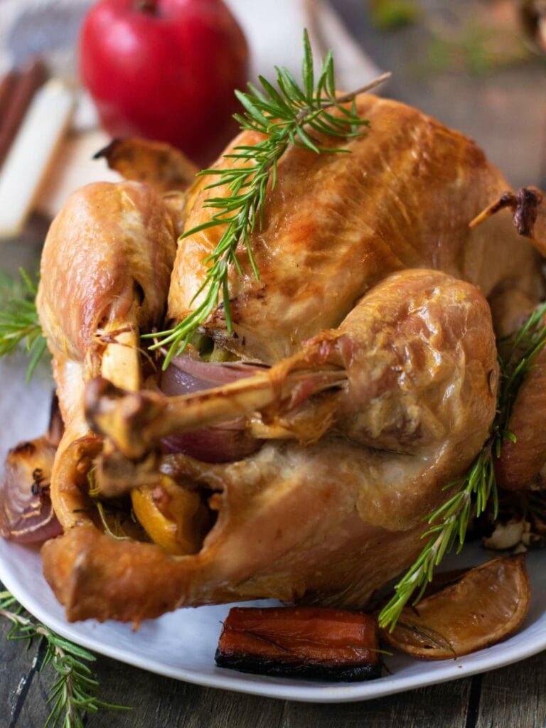 Roasted turkey garnished with fresh rosemary on a white plate.