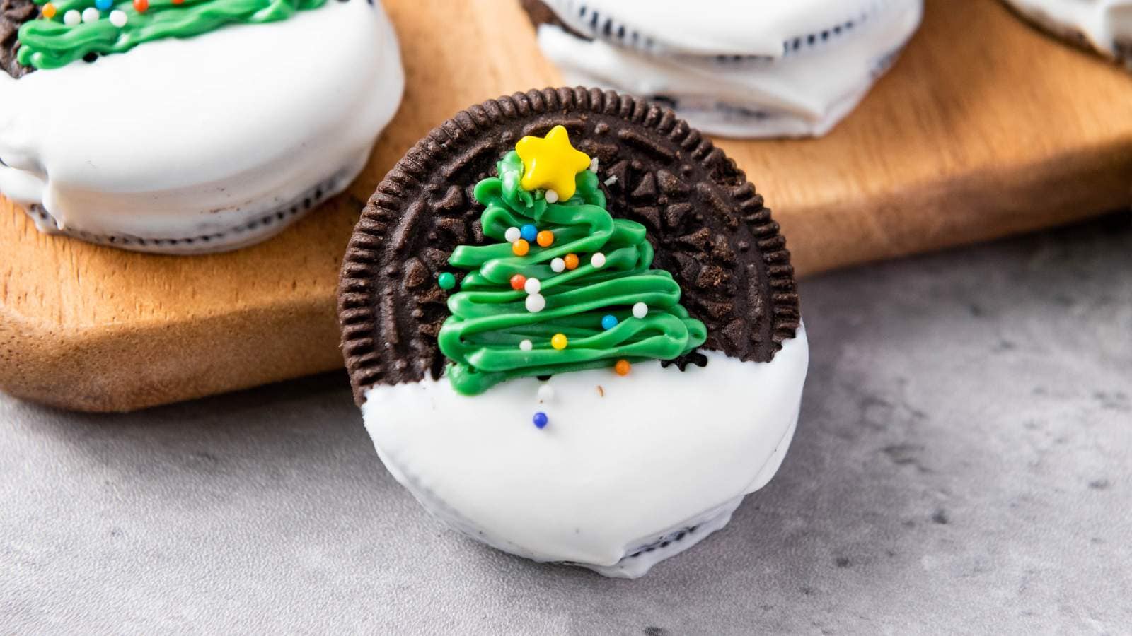 Christmas tree oreos decorated and placed on a wooden board.