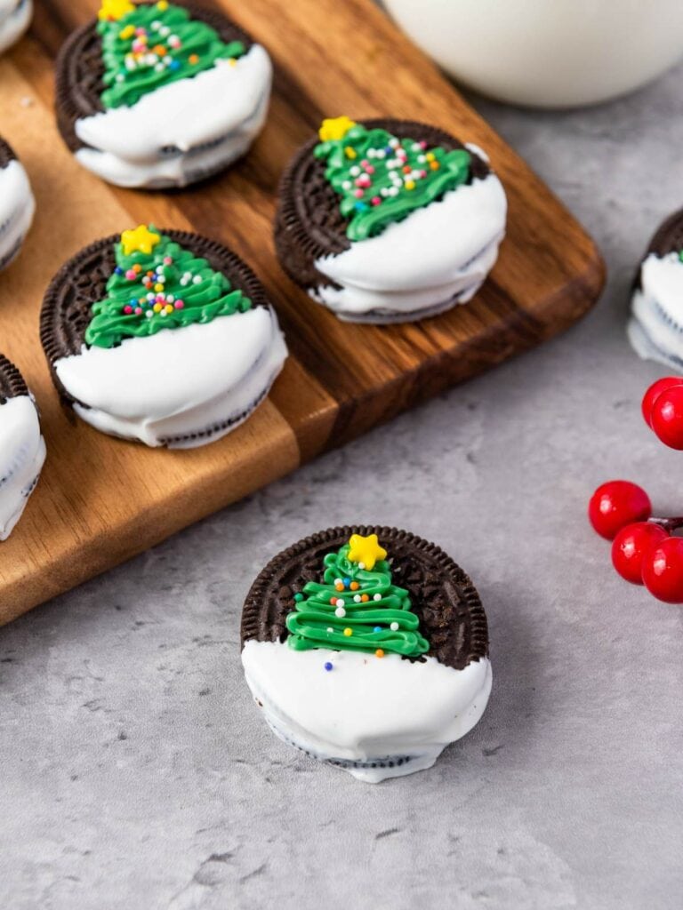 Christmas tree oreos on a wooden board and a gray surface.