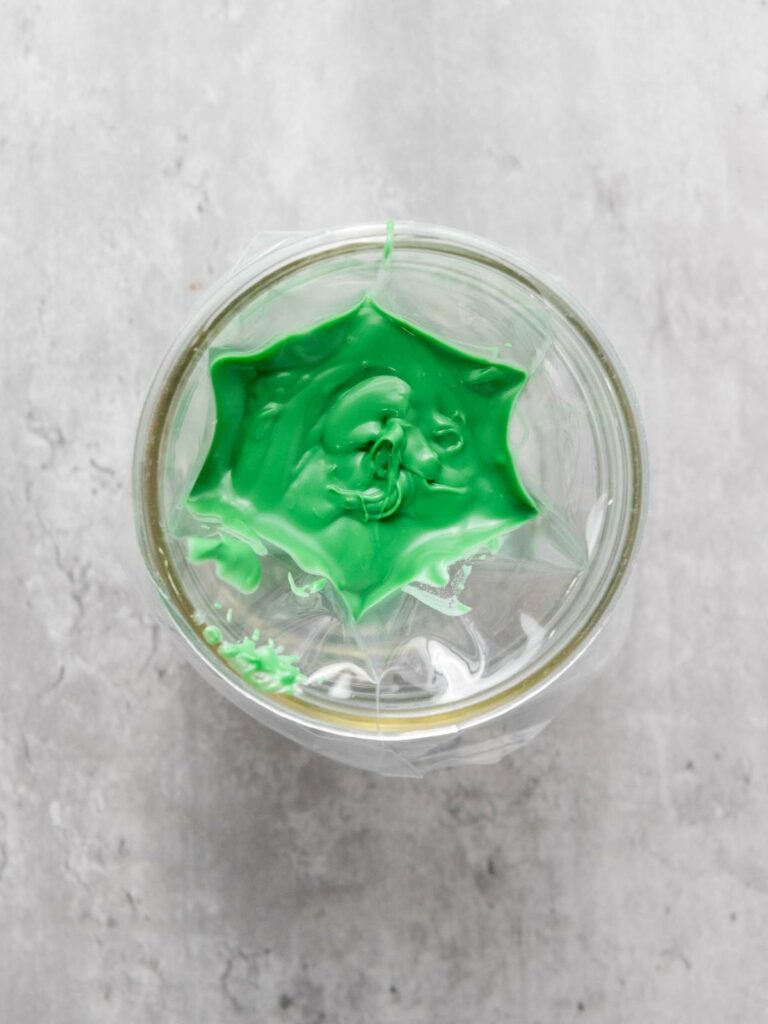 A glass jar with green paint splattered inside, creating a starburst pattern.