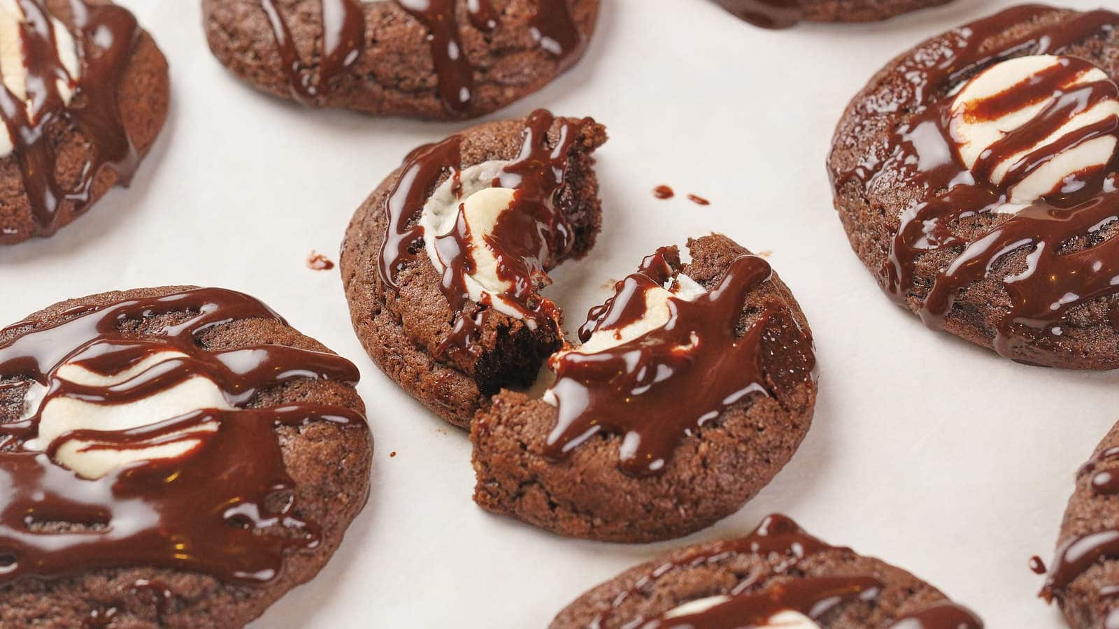 Chocolate cookies with melted chocolate drizzle, some topped with white chocolate chunks.