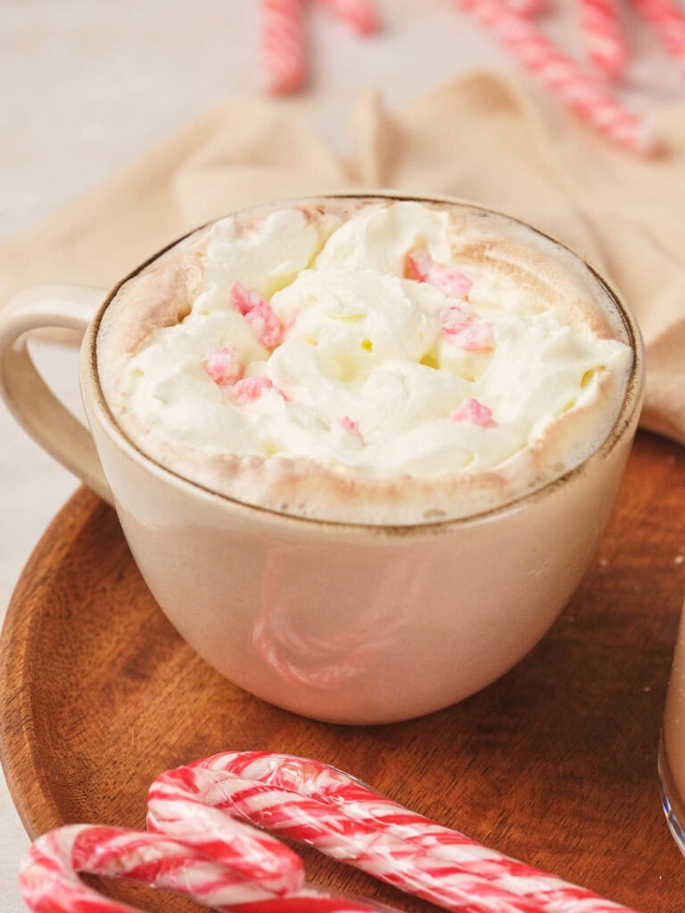 A mug of peppermint mocha topped with whipped cream and pink sprinkles.