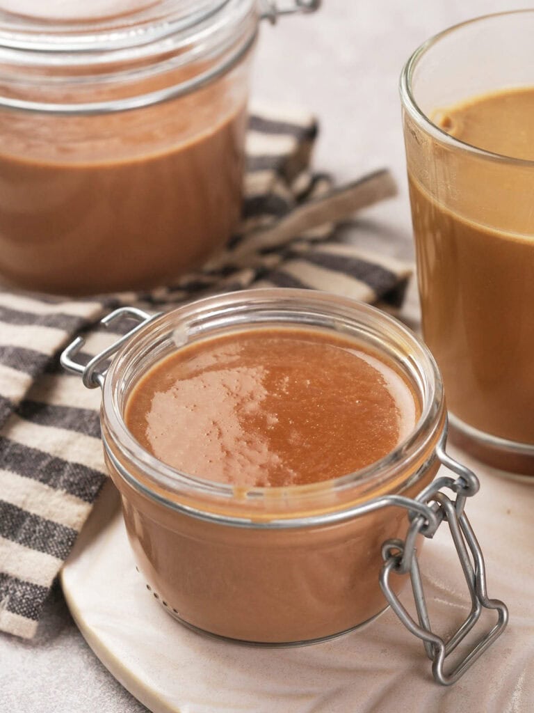 Close-up of a glass jar containing peppermint mocha coffee creamer on a striped cloth.