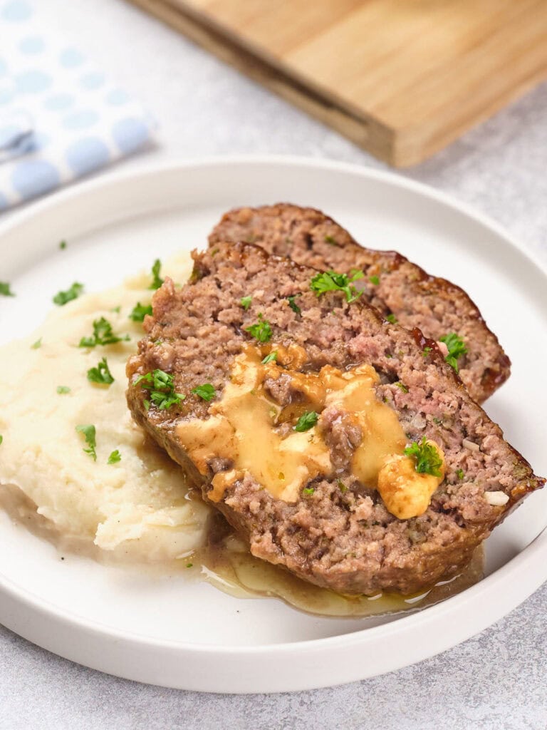 Slices of stuffed meatloaf topped with sauce and garnished with parsley.